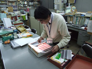 3月の寄贈品コーナー展示「道了尊　星の参道」の準備作業をする沢村学芸員。