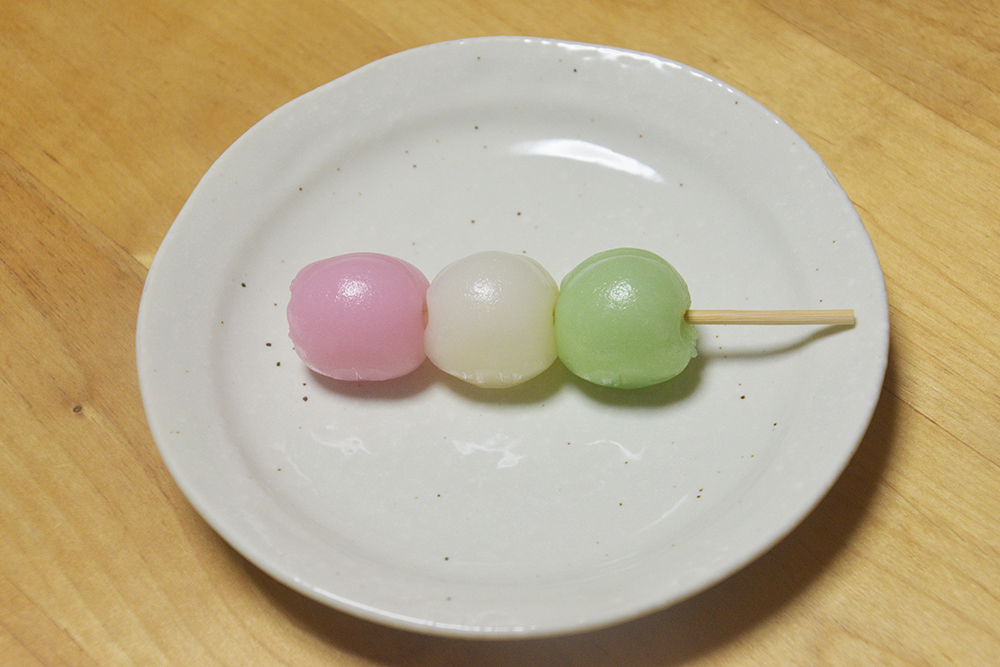串にささったピンク、白、緑の団子が皿に乗っている。