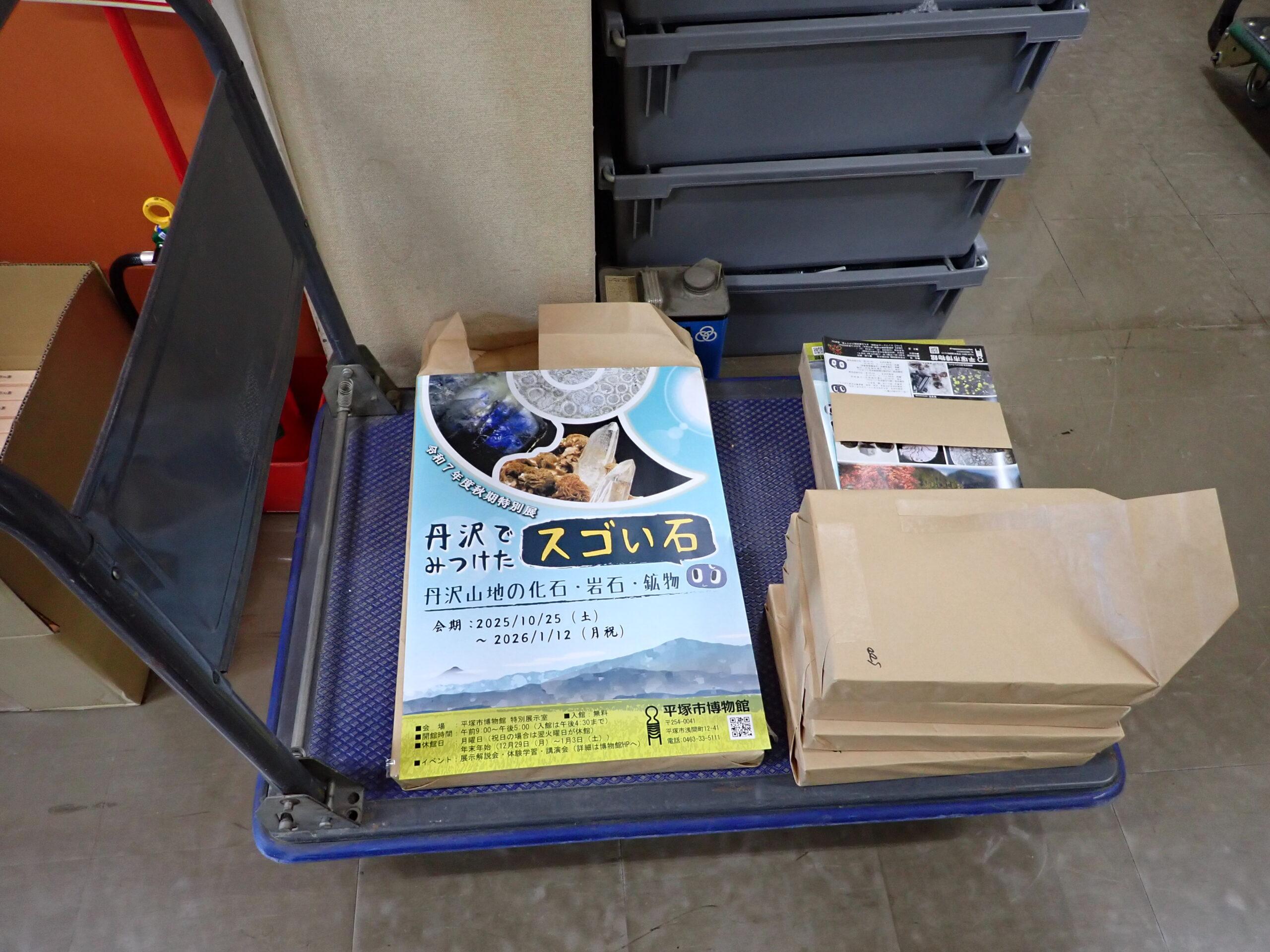 台車に載せられたポスターとちらしの束。検品のために開封した跡がある。