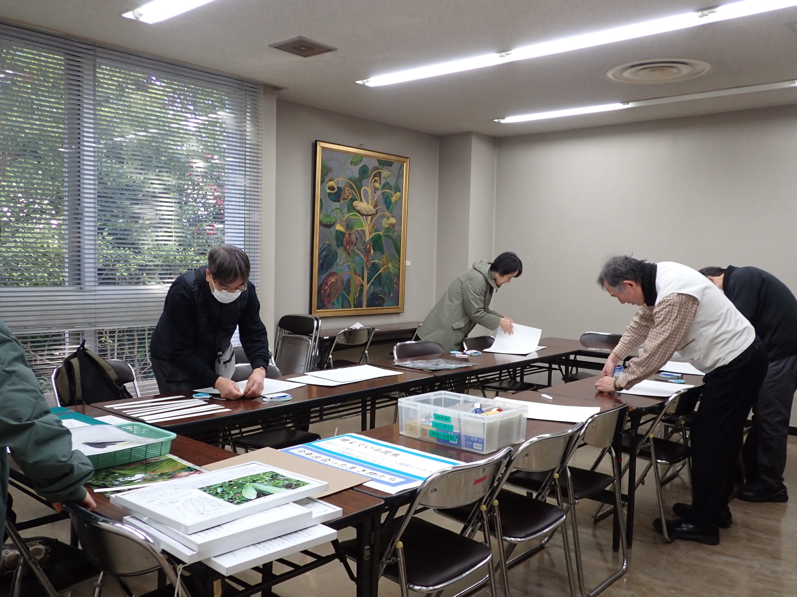 作業の様子。裏返した写真に4人でテープを貼っている。